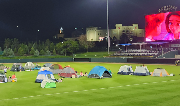 a green baseball field with pop up camping tents scattered