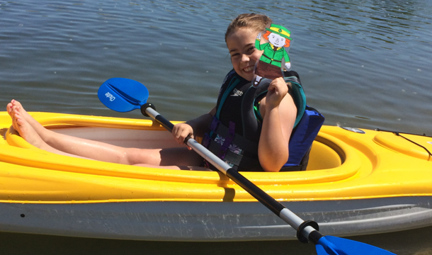 girl in a kayak holding a paddle and a paper doll