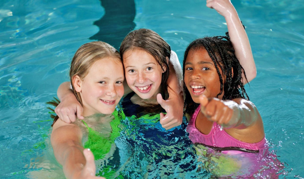 three girls having fun swimming in an indoor pool