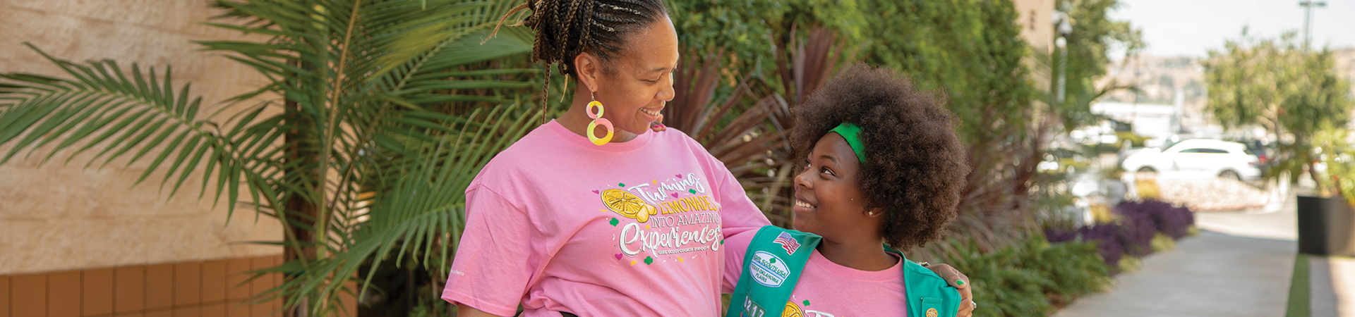  a mother and daughter standing in front of tropical plants looking at one another and smiling 