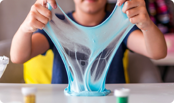 Two girls in Brownie Girl Scout uniforms stretching and playing with homemade slime