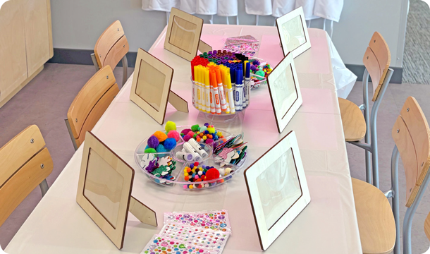 Two girls wearing an orange aprons at a table with painting supplies